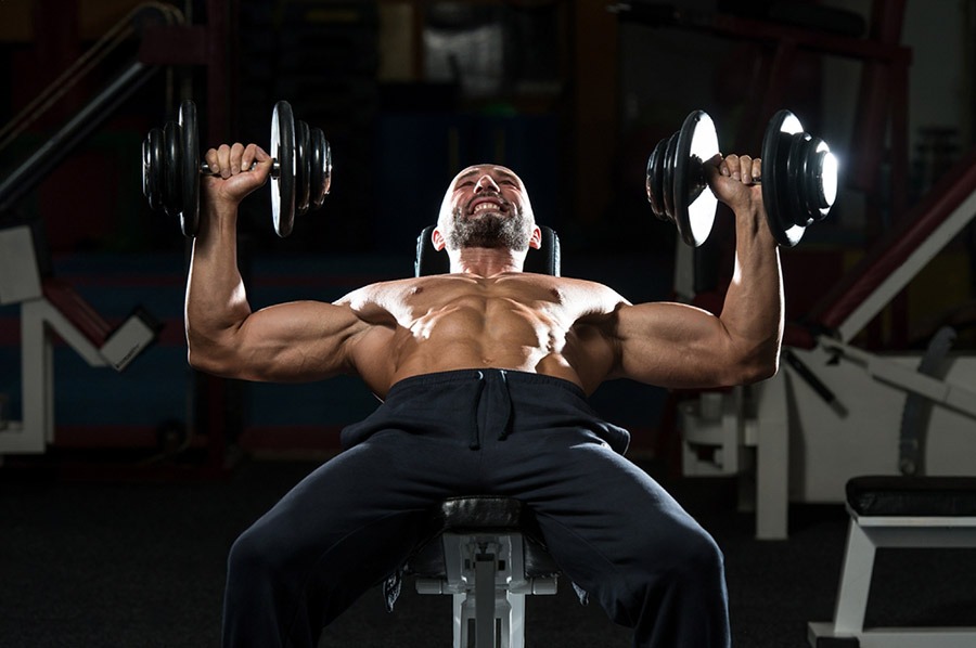 Man using incline dumbbell press to sculpt chest muscles in gym setting